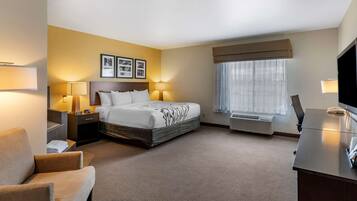 A hotel room with a bed, bedside lamps, a desk, a chair, and a TV.