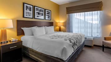 A hotel room with a bed, bedside lamps, a nightstand, a chair, and a window with curtains.