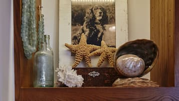 Una repisa con diversos objetos decorativos, incluyendo un modelo de coche antiguo, una estrella de mar y una fotografía enmarco.