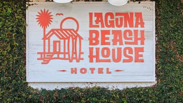 A sign for Laguna Beach House Hotel with a simple graphic of a house and sun.