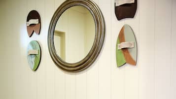A wooden bench with colorful cushions against a white paneled wall, flanked by decorative mirrors.