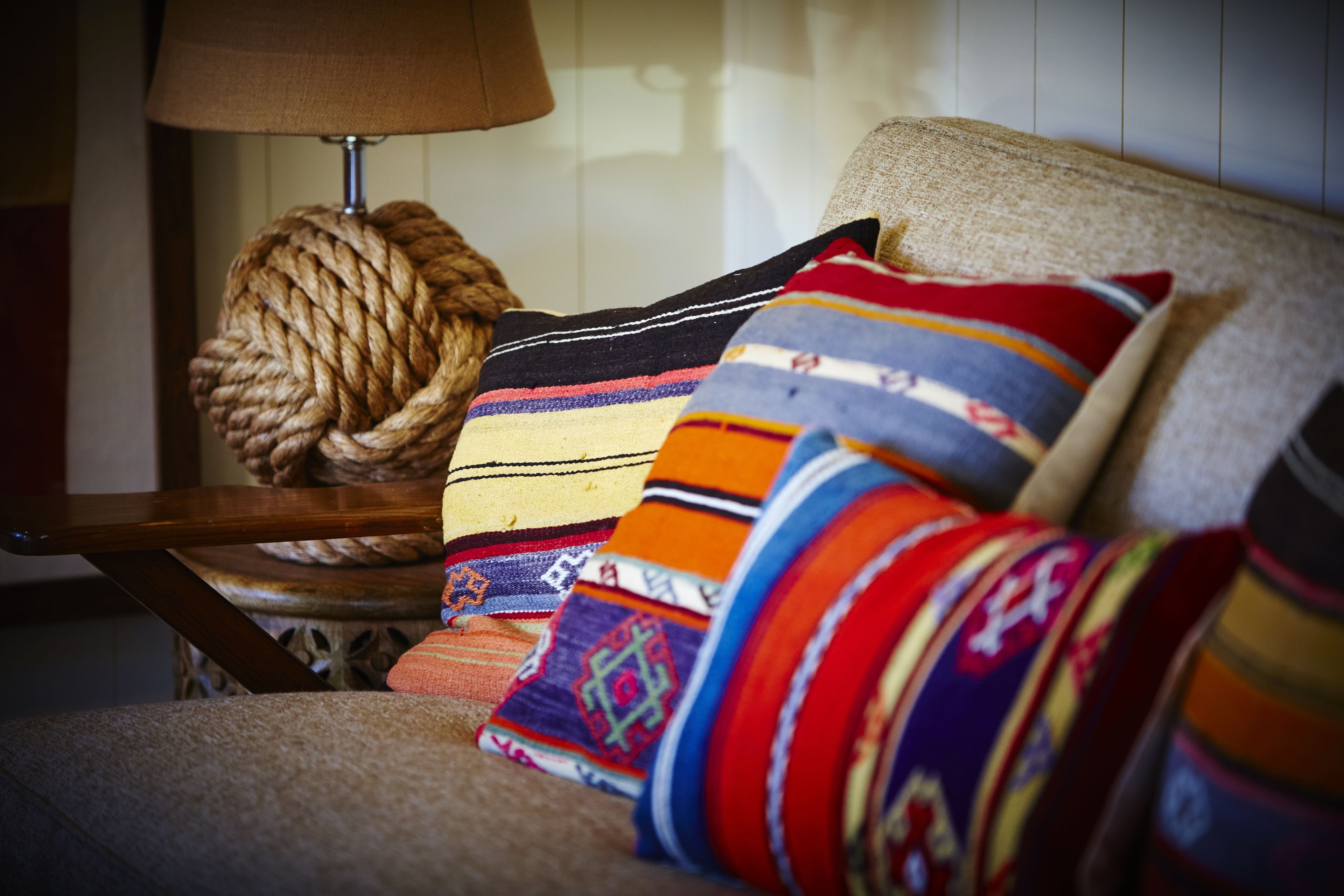 A chair with a woven ball and colorful pillows.