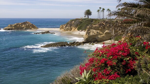 A coastal landscape with rocky cliffs, a sandy beach, and a clear blue sea. - Laguna Beach House (Laguna Beach)