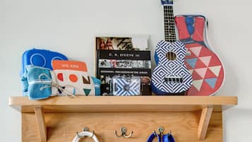 A wooden shelf with a guitar, a book, and bags.