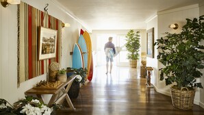 A hallway with surfboards, a chessboard, and various plants. - Laguna Beach House (Laguna Beach)