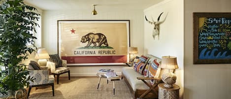 Una sala de estar acogedora con un gran mural de un oso, un sofá de madera, cojines estampados y un cráneo decorativo en la pared.
