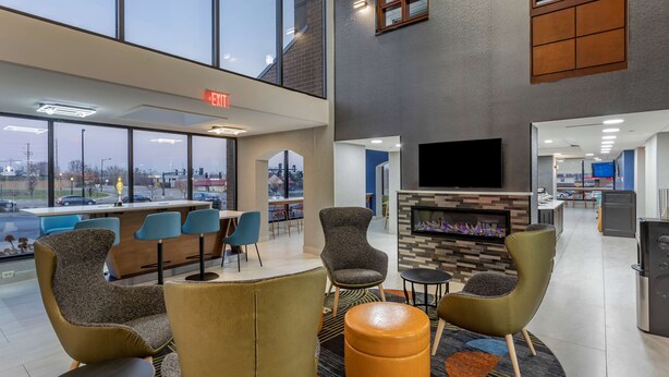 A modern lobby with a fireplace, comfortable seating, and a large TV screen.