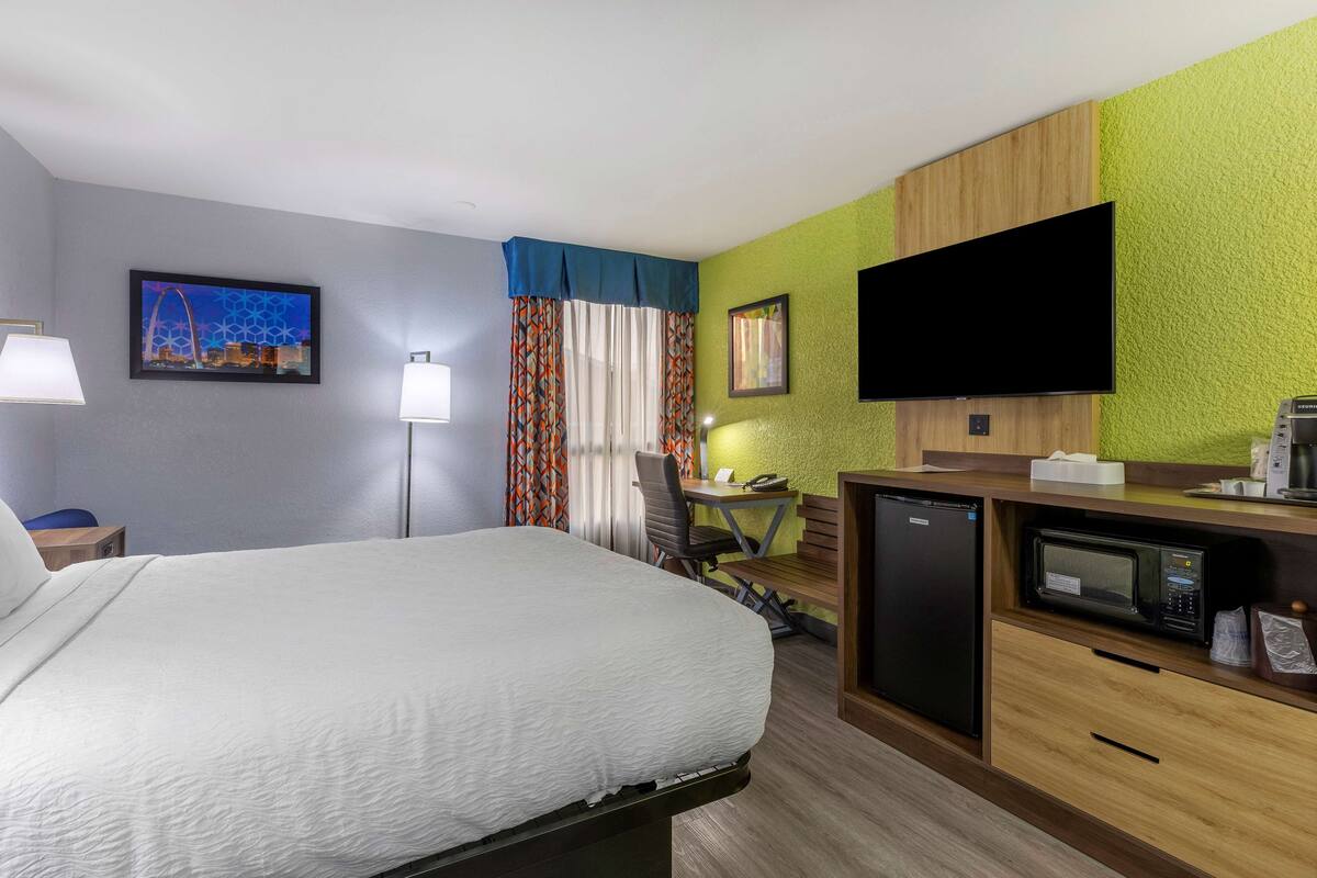 Een hotelkamer met een bed, bureau, stoel, televisie en een magnetron.