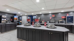A modern kitchen with dark cabinets, a central island, and various appliances including a coffee machine and a microwave.