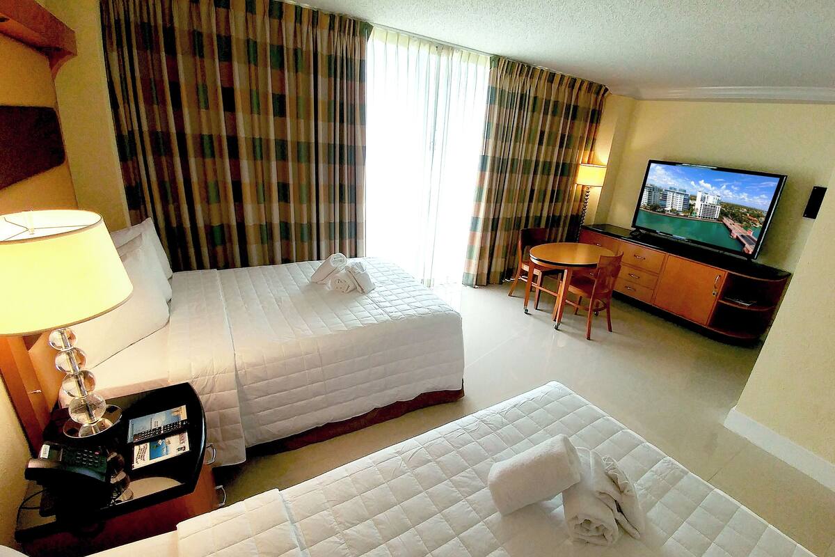 Une chambre d’hôtel comprenant un lit, un bureau avec un téléphone, une télévision, une chaise et une petite table.