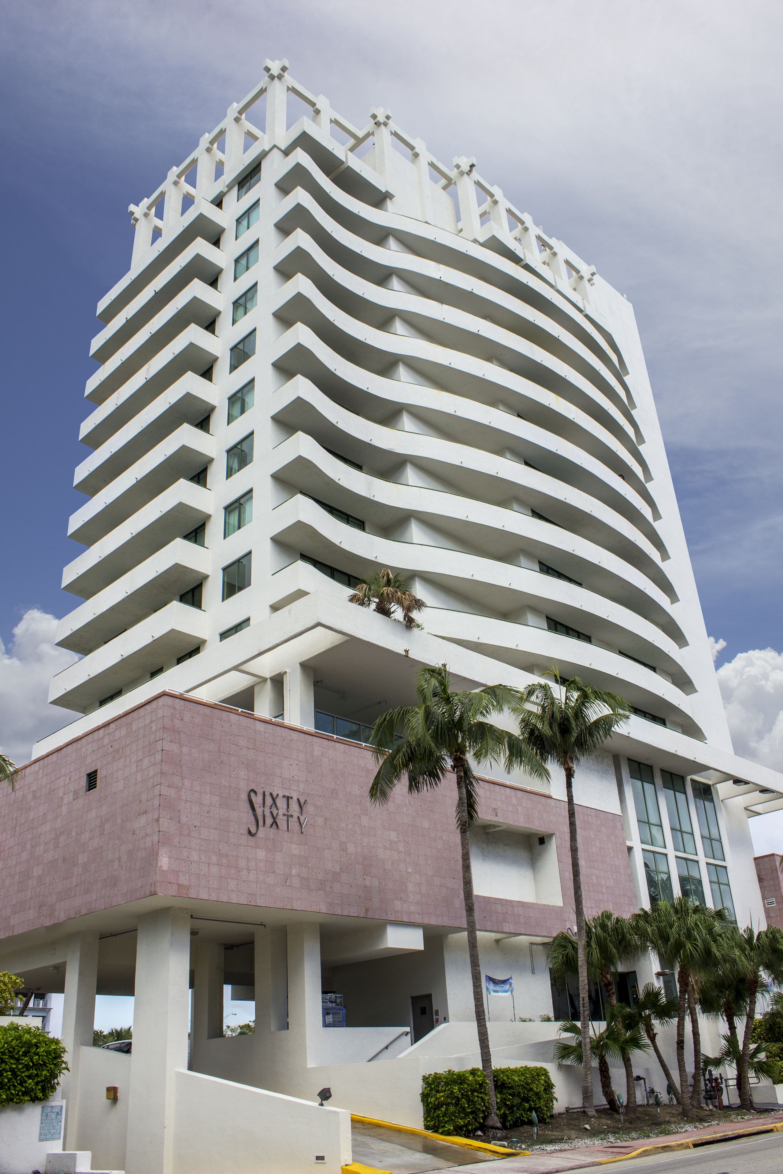 A modern hotel with a curved facade, multiple balconies, and a sign reading "Sixty".