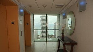 A hotel corridor with a view of a tall building and the sea. - Sixty Sixty Resort (Miami Beach)