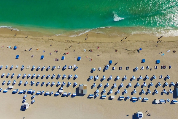 Pantai di sekitar, pasir putih, kursi berjemur, dan handuk pantai