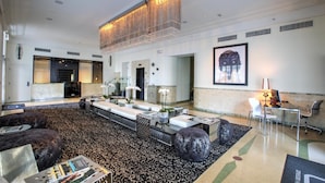 A spacious lobby with a high ceiling, a central seating area with sofas and a coffee table, and a reception desk with chairs.