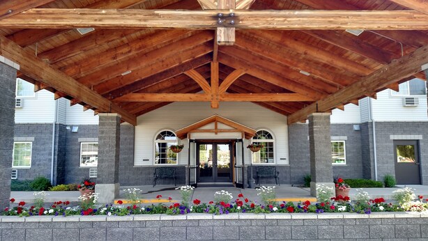 A covered outdoor area with a wooden ceiling, stone walls, and a central entrance. - Choteau Stage Stop Inn (Choteau)