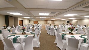 A conference room with rows of tables and chairs, each table adorned with a green table runner and floral centerpieces. - Choteau Stage Stop Inn (Choteau)