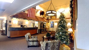 A lobby with a reception desk, a Christmas tree, and patterned armchairs. - Choteau Stage Stop Inn (Choteau)