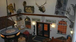 A room with a large wooden ceiling, a round table, and a door leading outside. - Choteau Stage Stop Inn (Choteau)