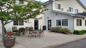 A building with a patio area featuring outdoor furniture and a tree. - Choteau Stage Stop Inn (Choteau)