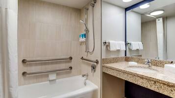 Un baño moderno con bañera, ducha y tocador con lavamanos y espejo.