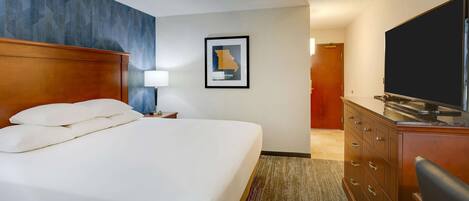A hotel room with a large bed, a wooden headboard, a flat-screen TV, a dresser, and a framed map on the wall.