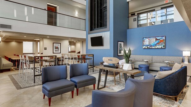 A spacious lobby with a high ceiling, a dining area, and a seating area with sofas and a coffee table. - Drury Inn & Suites St. Louis St. Peters (St. Peters)