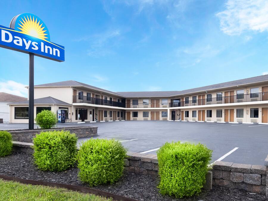 Um Days Inn com um amplo estacionamento, um pátio central e uma fileira de quartos de motel.