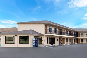 Un motel à plusieurs étages, doté d’un toit plat, de grandes fenêtres et d’un parking.