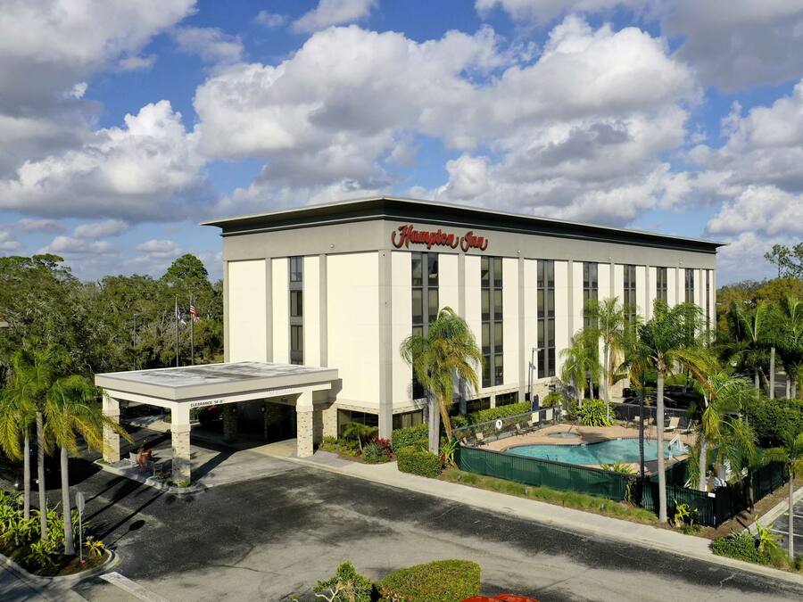 A Hampton Inn hotel with a pool, surrounded by palm trees and greenery.