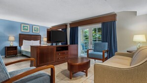 Ein Hotelzimmer mit einem Bett, einem Fernseher, einem Holzschrank, einem Sofa, einem Sessel und einem kleinen Tisch.