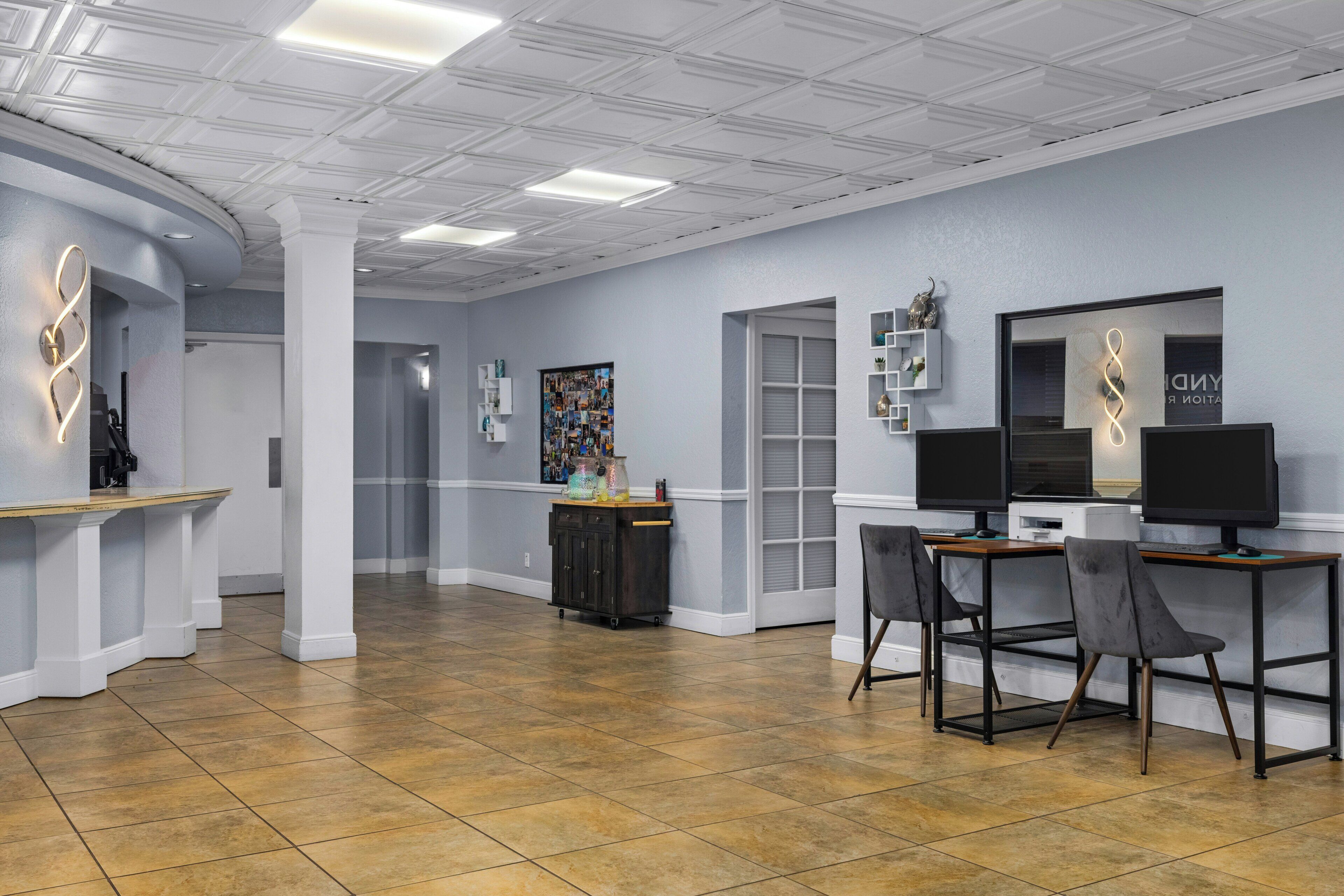 A modern interior with a reception desk, two computer stations, and a tiled floor.