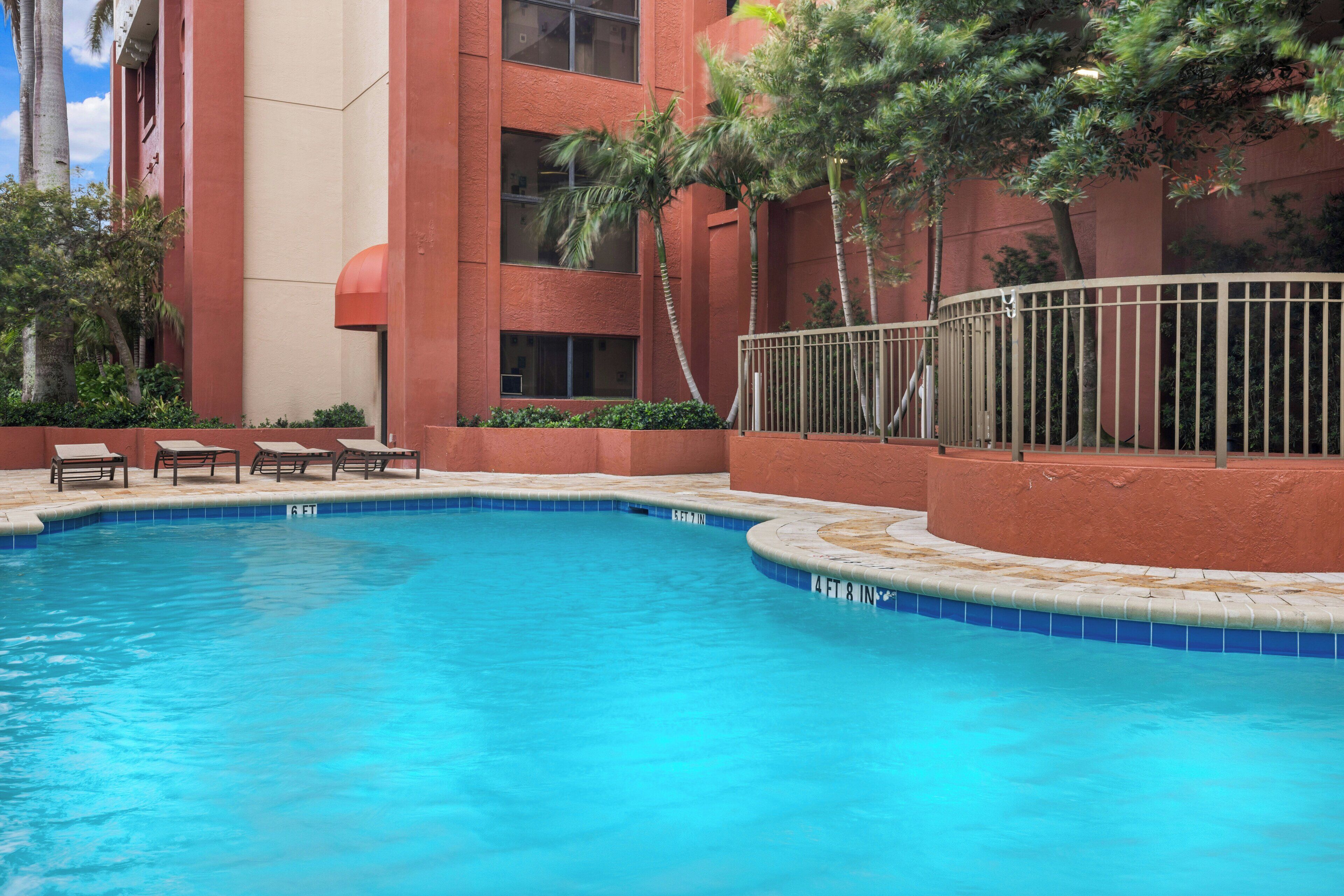 A swimming pool with a tiled edge, surrounded by a low wall and benches.
