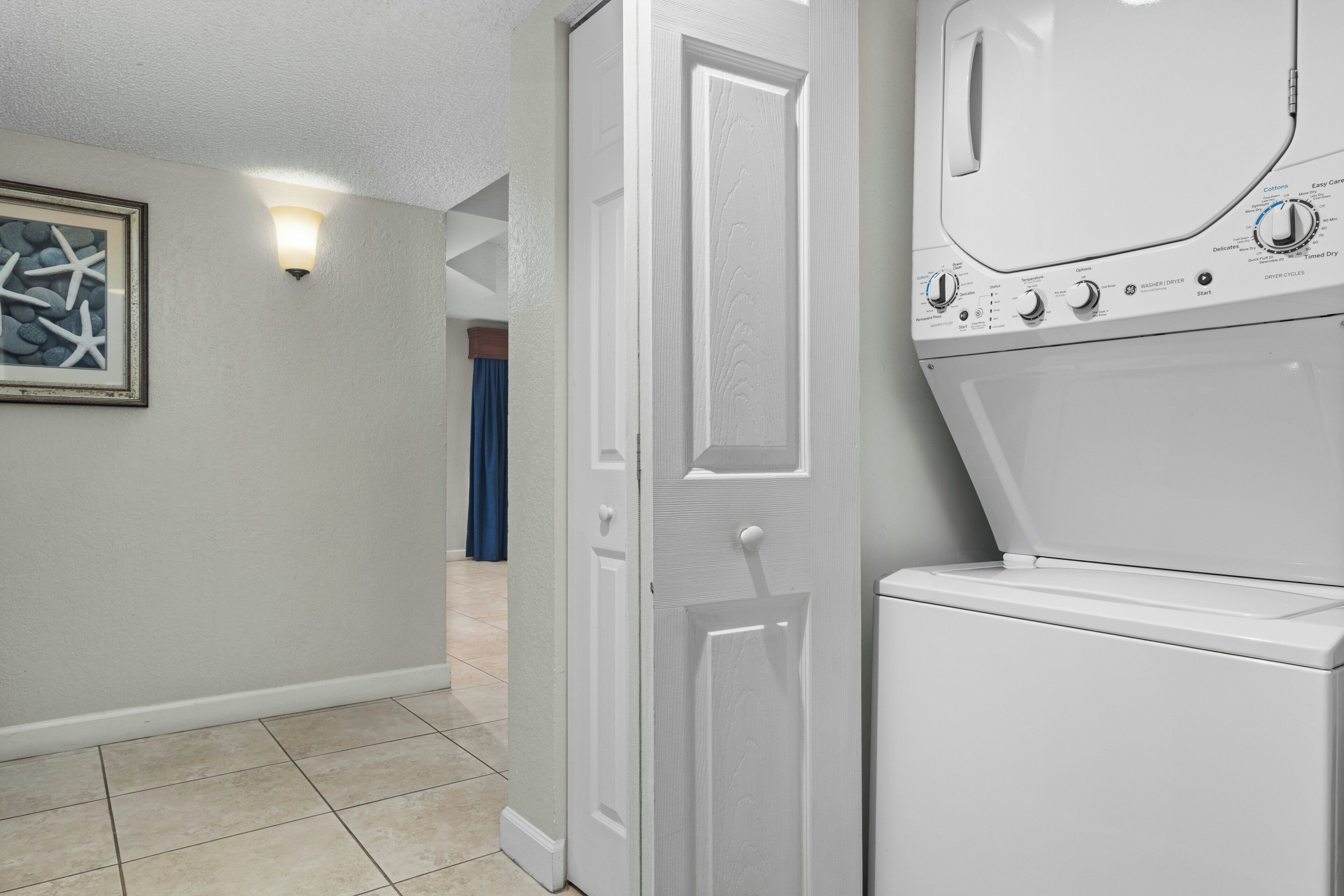 A laundry room with a washing machine and dryer, a door, and a light fixture on the wall.