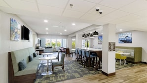 A hotel lobby with a sofa, dining area, and a pool sign. - Hampton Inn Port Charlotte (Port Charlotte)