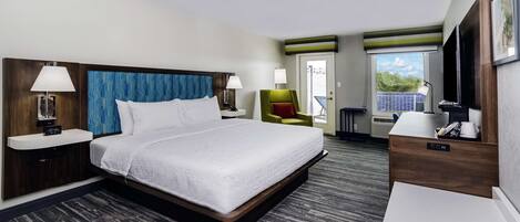 Habitación de hotel con una cama grande, mesitas de noche, un escritorio, una silla y una ventana con vistas.