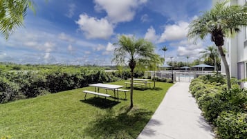 A well-maintained outdoor area with picnic tables, a pathway, and lush greenery.