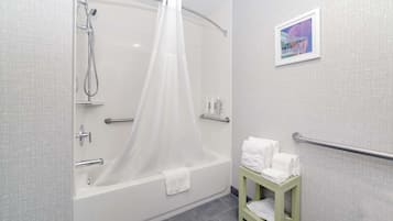 A modern bathroom with a glass-enclosed shower, a bathtub, and a small stool with towels.