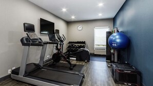 A gym with a treadmill, exercise bike, dumbbells, a blue medicine ball, and a weight bench. - Hampton Inn Port Charlotte (Port Charlotte)