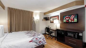 Una habitación de hotel con cama, escritorio, televisor y microondas.