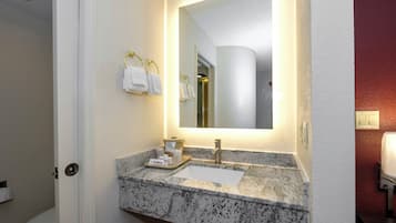 Un baño con lavamanos de mármol, un espejo y un perchero para toallas.