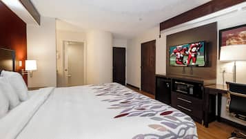 Habitación de hotel con cama, televisión, escritorio con silla y microondas.
