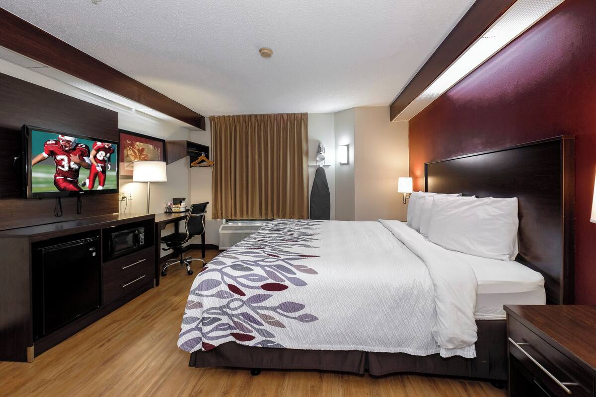 Una camera d'albergo con un letto, una scrivania, una televisione e un armadio.