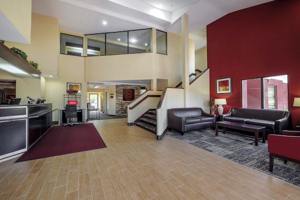 A spacious lobby with a staircase, seating area, and a reception desk.