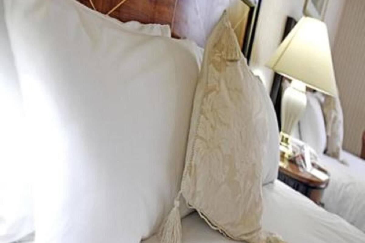 A neatly made bed with white linens and a decorative pillow.