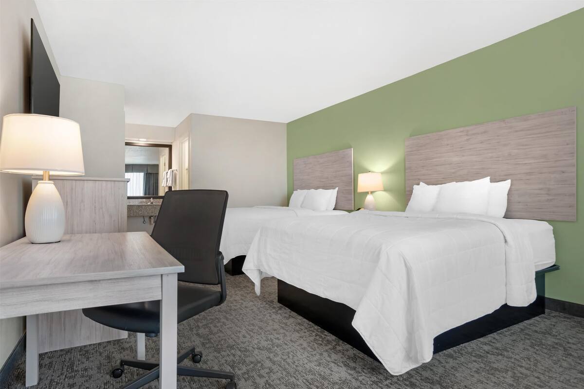 Ett hotellrum med två sängar, ett skrivbord och en stol.