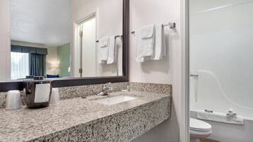 A bathroom with a granite countertop, a sink, a mirror, a towel rack, a toilet, and a bathtub.