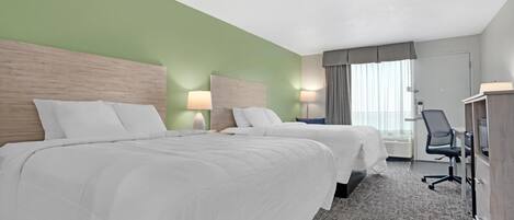 A hotel room with two beds, a desk, and a chair.