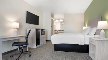 A hotel room with a bed, desk, chair, TV, and bedside lamps.