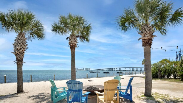 A beachside seating area with chairs and a fire pit, palm trees, and a view of the ocean and pier. - Best Western Navarre Waterfront (Navarre)