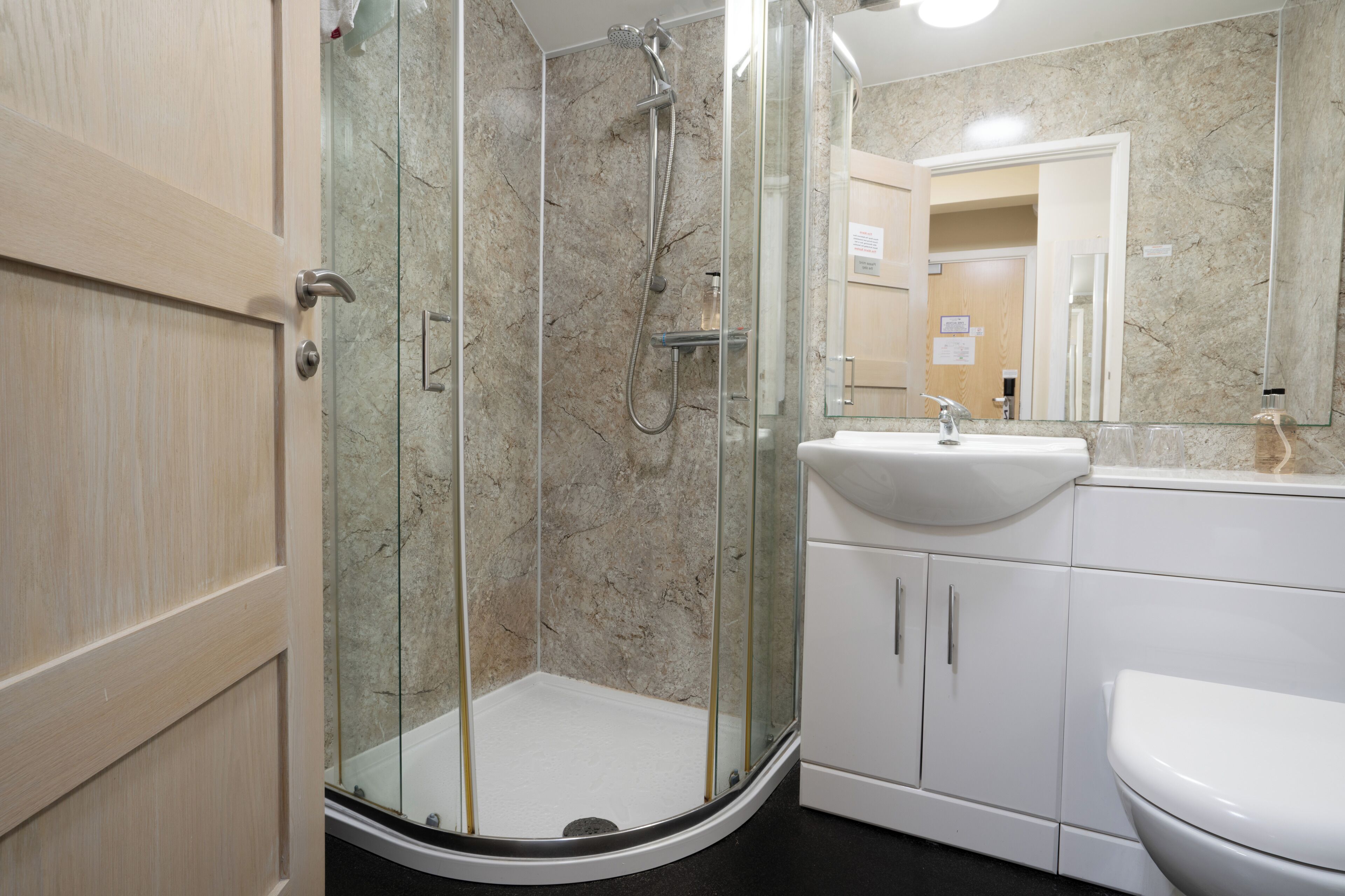 A modern bathroom with a glass-enclosed shower, a white sink, and a large mirror.